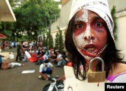 Seorang aktivis pelajar Indonesia mengikat mulutnya untuk melambangkan kurangnya kebebasan berbicara saat melakukan protes di depan kantor Komisi Hak Asasi Manusia di Jakarta Pusat. (Foto: Reuters)