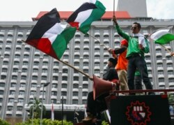 Seorang anggota organisasi buruh Indonesia memegang bendera Palestina saat melakukan aksi protes terhadap Israel di luar gedung PBB di Jakarta, 18 Mei 2021. (Foto: REUTERS/Ajeng Dinar Ulfiana)