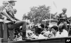 FILE - Members of the Youth Wing of the Indonesian Communist Party are guarded by soldiers as they are taken by an open truck to prison in Jakarta after they were rounded up by the army following a crackdown on communists after an attempted coup, Oct. 30, 1965.