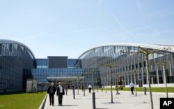 People walk outside the entrance of the new NATO headquarters in Brussels on April 19, 2018. NATO ministers will hold their last meeting in the old headquarters on April 27, 2018 before moving permanently to a new building across the street.