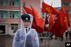 FILE - A North Korean traffic police woman directs vehicles at a street junction while behind her the sidewalk is decorated with flags of the ruling party, the Workers' Party on May 5, 2016, in Pyongyang, North Korea.