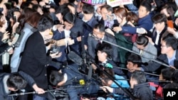 Choi Soon-sil (tengah, bertopi hitam), dikelilingi jaksa penuntut dan wartawan di pengadilan di Seoul, Oktober 2016.