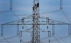 FILE - Workers of the German energy company RWE prepare power supply on a high power pylon in Moers, Germany, April 11, 2011.
