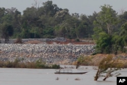FILE - In this June 20, 2016 file photo, a fishing boat passes near a construction site of the Don Sahong dam, near Cambodia-Laos borders, in Preah Romkel village, Stung Treng province, northeast of Phnom Penh, Cambodia.