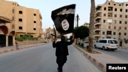 Seorang anggota yang loyal terhadap Negara Islam di Irak dan Syam (ISIS) mengibarkan bendera ISIL di Raqqa pada 29 Juni 2014. (Foto: Reuters)