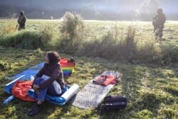 Tentara Polandia dan petugas patroli perbatasan menjaga sekelompok migran yang terdampar di perbatasan antara Belarus dan Polandia di dekat desa Usnarz Gorny, Polandia, 22 Agustus 2021. (Foto: Grzegorz Dabrowski/Agencja Gazeta via REUTERS)