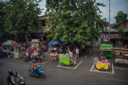 Para pedagang kaki lima menempati tempat yang disediakan untuk memastikan jarak aman di tengah wabah virus corona, saat bulan Ramadan, di Surabaya, 29 April 2020.