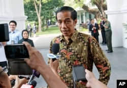 FILE - Indonesian President Joko Widodo, center, talks to the media at Merdeka Palace in Jakarta, Indonesia, Oct. 21, 2014.