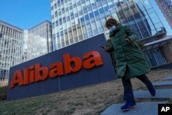 Seorang perempuan melewati kantor perusahaan e-commerce China Alibaba di Beijing pada 13 Desember 2021. (Foto: AP)