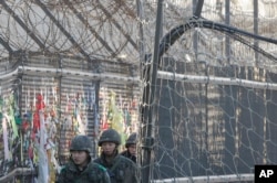 South Korean Army soldiers patrol by ribbons, wishing for the reunification of the two Koreas, attached on the barbed-wire fence in Paju, near the border with North Korea, South Korea, Feb. 7, 2016.