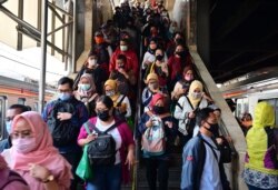 Para komuter yang mengenakan masker wajah berjalan ke peron kereta mereka di stasiun kereta Tanah Abang di Jakarta pada 18 Agustus 2020. (Foto: AFP/Adek Berry)