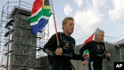 FILE - South African runner Braam Malherbe, left, and Dawid Grier run past the prison where former South African President Nelson Mandela spent most of the 27 years that he was jailed, during his 90th birthday celebration on Robben Island, South Africa, July 18, 2008.