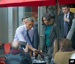 President Barack Obama, accompanied by first lady Michelle Obama, greets patrons after they had lunch with members of the Standing Rock Sioux Tribal Youth at We the Pizza/Good Stuff Eatery restaurant in the Capitol Hill neighborhood of Washington, DC, Nov. 20, 2014.