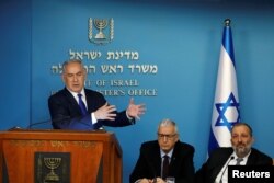 Israeli Prime Minister Benjamin Netanyahu gestures during a news conference as he stands next to Shlomo Mor-Yosef, Director General of the Israeli Population and Immigration Authority, and Israeli Interior Minister Aryeh Deri at the Prime Minister's office in Jerusalem, April 2, 2018.