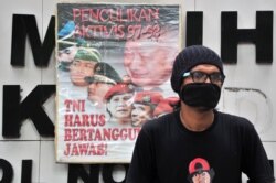 Seorang pengunjuk rasa duduk di samping spanduk yang bertuliskan "Penculikan Aktivis 1997-1998, TNI Harus Bertanggung Jawab" saat melakukan protes terhadap Prabowo Subianto di Jakarta, 20 Mei 2014. (Foto: dok).