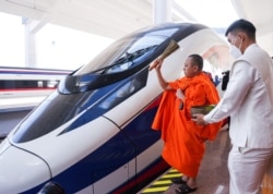 Seorang biksu memberkati kereta api dalam upacara Buddhis, satu hari sebelum upacara serah terima proyek kereta api berkecepatan tinggi yang menghubungkan kota Kunming dengan Vientiane di barat daya China, di Vientiane, Laos, 2 Desember 2021. (Foto: REUTER