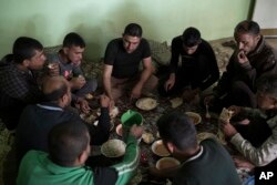 Firas Mohammed al-Jibouri, top right, eats lunch with family members inside his house in Mosul, Iraq, April 5, 2017.