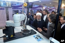 FILE - In this photo released by an official website of the office of the Iranian Presidency, President Hassan Rouhani listens to explanations on new nuclear achievements at a ceremony to mark "National Nuclear Day," in Tehran, Iran, April 9, 2018.