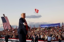 Presiden AS Donald Trump melempar masker dari panggung dalam kampanye pertamanya sejak dirawat karena terinfeksi virus corona (COVID-19) di Bandara Internasional Orlando Sanford di Sanford, Florida, Senin, 12 Oktober 2020. (Foto: Reuters)