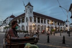Seorang tukang becak bermasker duduk menunggu pelanggan di lokasi wisata Kota Tua, Semarang, Jawa Tengah, 1 Juli 2021. (Foto: Antara/Aji Styawan via REUTERS)