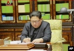 This image made from video of a news bulletin aired by North Korea's KRT on Nov. 29, 2017, shows an image of North Korea's leader Kim Jong Un signing what is said to be a document on Nov. 28, 2017, authorizing a missile test.