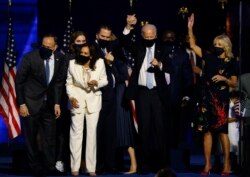 Calon presiden AS dari Partai Demokrat 2020 Joe Biden mengangkat tangan putranya Hunter, saat mereka dan calon wakil presiden Kamala Harris dan keluarga mereka merayakan di atas panggung saat kampanye. (Foto: Reuters / Jim Bourg)