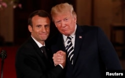 French President Emmanuel Macron clasps hands with President Donald Trump at the conclusion of their joint news conference in the East Room of the White House in Washington, April 24, 2018.