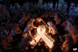 Mahasiswa kedokteran menyalakan lilin pada acara peringatan Hari AIDS Sedunia di Surabaya, Jawa Timur, Senin, 1 Desember 2015. (Foto: AP)
