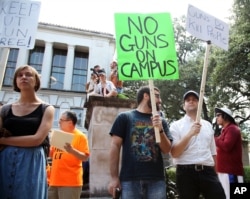 Students holds signs and sex toys as they protest a campus carry law in Austin, Texas, Aug. 24, 2016.