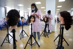 FILE - Students braid wigs during a class at the Peyzawat Training School in Peyzawat County in China's far west Xinjiang region, as seen during a state-organized tour for foreign media, April 19, 2021.