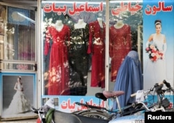 Seorang perempuan mengenakan burqa berjalan melewati toko pakaian perempuandengan manekin tanpa kepala yang dipajang di jendelanya, di Kabul, Afghanistan, 19 Oktober 2021. (Foto: Reuters)