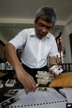 លោក ឆាំង យុ នាយក​មជ្ឈមណ្ឌល​ឯកសារ​កម្ពុជា ជ្រើស​រើស​រូបថត​មួយ​ចំនួន​ក្នុង​ចំណោម​រូបថត​រាប់​ពាន់​នៃ​អតីត​អ្នក​ទោសគុក​ទួលស្លែង នៅ​ក្នុង​ការិយាល័យ​របស់​លោក​នៅ​រាជធានី​ភ្នំពេញ​កាល​ពី​ថ្ងៃ​ទី​២០ ខែ​សីហា ឆ្នាំ​២០១២។