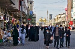 Warga Irak berbelanja di kawasan Khadimiyah sebelum diberlakukannya jam malam oleh pihak berwenang untuk menekan penyebaran COVID-19, 18 Februari 2021.