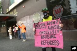 Pengunjuk rasa membentangkan spanduk di luar Park Hotel menyerukan pembebasan pengungsi yang ditahan di dalamnya di Melbourne, Australia, 8 Januari 2022. (Foto: AP)