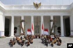 Presiden Joko Widodo (baris atas ke-5 dari kiri) dan Wakil Presiden Ma'ruf Amin (ke-6 dari kiri) bersama menteri-menteri kabinet baru duduk di tangga saat mengumumkan nama menteri-menteri baru, Rabu, 23 Oktober 2019. (Foto: AP)