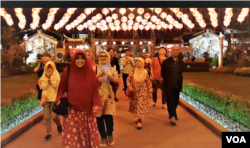 Pengurus kelenteng Xie Tian Gong, Sugiri Kustedja (kanan) berjalan di depan kelenteng bersama para peserta tur malam Imlek, Selasa (5/2/2019) malam. (VOA/Rio Tuasikal)