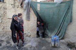 Seorang bocah laki-laki yang mengungsi mengintip melalui tirai rumah sementara di kota Kabul, Afghanistan, Rabu, 30 Desember 2020. (Foto: AP)