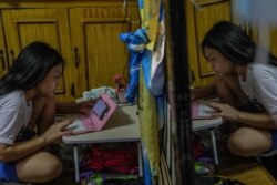 Maria Conception Relloma, mahasiswa yang baru memasuki tahun pertamanya, mulai mengikuti kuliah daringnya dari rumah dengan menggunakan ponsel dan modul pembelajaran tercetak pada pembukaan sekolah di pinggiran kota kota Mandaluyong Manila, 5 Oktober 2020.(Foto oleh Maria Tan / AFP)