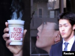 Seorang pria melewati iklan pembuat mie instan terkemuka Jepang Nissin Food Products dengan pemain golf bintang Michelle Wie memegang "Cup Noodle", di kantor pusat perusahaan di Tokyo. (REUTERS/Toshiyuk Aizawa)