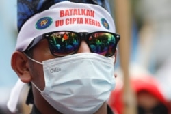 Seorang anggota serikat buruh mengenakan ikat kepala bertuliskan "batalkan UU Cipta Kerja" dalam demo saat Mahkamah Konstitusi membacakan putusan uji materi UU Cipta Kerja, di Jakarta, Senin, 25 November 2021. (Foto: Ajeng Dinar/Reuters)