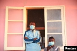 Tuberculosis patients, wearing masks to stop the spread of the disease, stand outside their ward at Chiulo Hospital, Cunene province, Angola, Feb. 22, 2018.