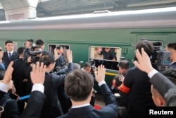 North Korean leader Kim Jong Un waves from a train, as he paid an unofficial visit to China, in this undated photo released by North Korea's Korean Central News Agency (KCNA) in Pyongyang, March 28, 2018.