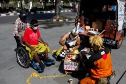 Sukarelawan Palang Merah Indonesia (mengenakan kostum wayang) membagikan makanan gratis, saat pemerintah melonggarkan pembatasan darurat di tengah pandemi COVID-19 di Solo, Jawa Tengah, 27 Juli 2021. (Antara Foto/Maulana S)