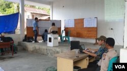 Seorang anggota Polisi (kanan) menjaga kegiatan rekapituasi suara tingkat Kecamatan Poso Kota Selatan, Kabupaten Poso, Sulawesi Tengah, 23 April 2019. (Foto: VOA/Yoanes Litha)