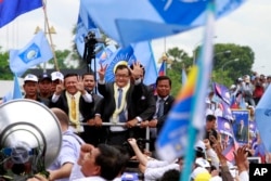 FILE - Sam Rainsy, center, president of Cambodia National Rescue Party (CNRP) greets his supporters together with his party's Vice President Kem Sokha, on Rainsy's left, on his arrival at Phnom Penh International Airport in Phnom Penh, Cambodia, Friday, July 19, 2013.