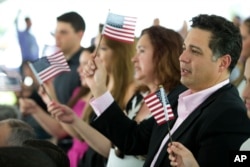 FILE - New citizens wave American flags during a U.S. Citizenship and Immigration Services naturalization ceremony on the campus of Florida International University in Miami, Florida, July 6, 2015.
