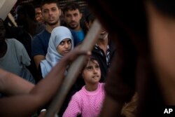 FILE - Migrants and refugees wait to leave the Golfo Azzurro rescue vessel as they arrive at the port of Pozzallo, south of Sicily, Italy, with hundreds of migrants aboard, rescued by members of Proactive Open Arms NGO, June 17, 2017.