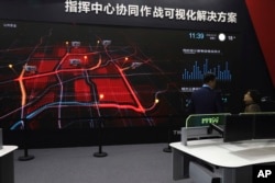 FILE - A visitor is briefed on a screen demonstrating city level surveillance at Security China 2018 expo in Beijing, Oct. 23, 2018.