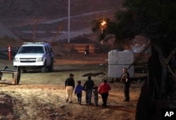 FILE - Migrants traveling with children walk up a hill to a waiting U.S. Border Patrol agent just inside San Ysidro, Calif., after climbing over the border wall from Playas de Tijuana, Mexico, Dec. 3, 2018.