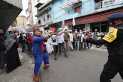Pendukung Rizieq Shihab, pemimpin Front Pembela Islam, menghadapi seorang polisi saat unjuk rasa di Jakarta, Jumat, 18 Desember 2020.
